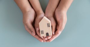 Adult woman and child hands holding a wood block home in their hands